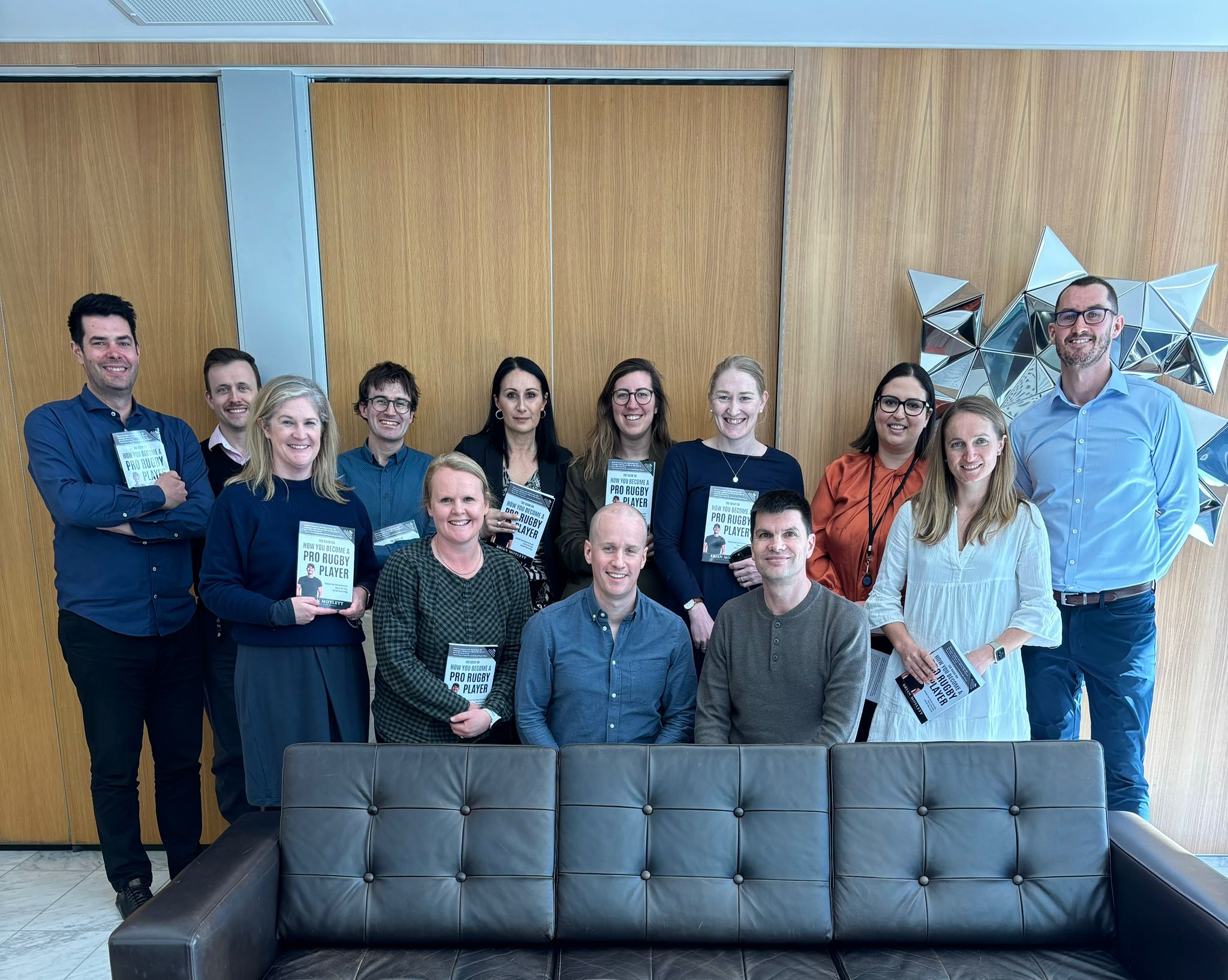 Brian Moylett with Senior Associates at Duncan Cotterill, Christchurch, New Zealand — each holding a copy of his book